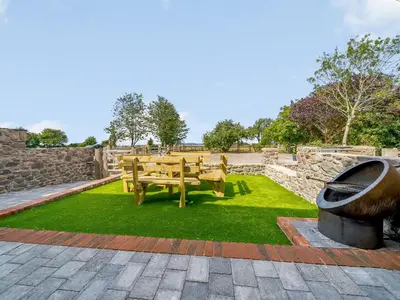 a wooden bench sitting on top of green grass at The Barnacle Goose - Uk35261 in Bowness-on-Solway