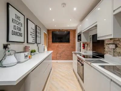 a kitchen with white cabinets and a brick wall at The Barnacle Goose - Uk35261 in Bowness-on-Solway