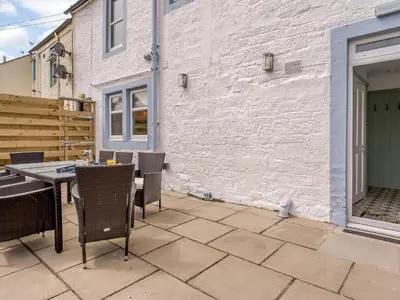a patio with a table and chairs and a building at Erriff At Caelaverock in Glencaple