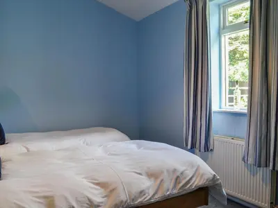 a bed in a blue room with a window at Lime Tree Cottage in Drumpark