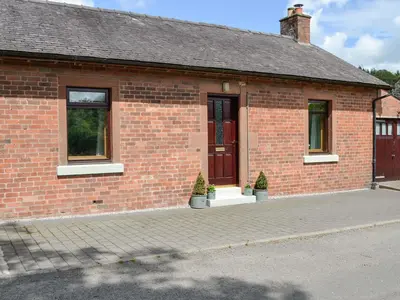 a brick building with two potted plants in front of it at Lime Tree Cottage in Drumpark