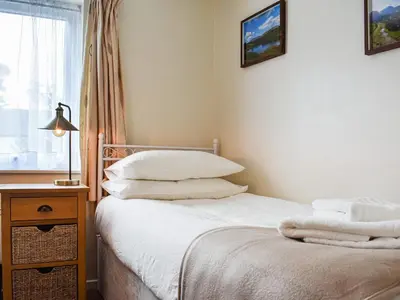 a bedroom with a bed with white sheets and pillows at Jane Eyre Cottage in Keswick