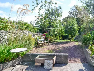 a garden with a table and a table and a bench at Oor Wee Hoose in Whithorn