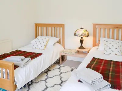 a bedroom with two beds and a lamp on a table at Oor Wee Hoose in Whithorn