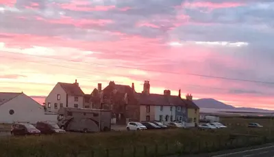 a group of houses and cars parked in a field at West View Cottage in Seaside Village of Allonby Cumbria in Allonby