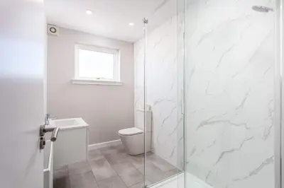 a bathroom with a toilet and a glass shower at The Orchard - Donnini Apartments in Ayr