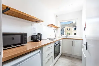 a kitchen with white cabinets and a wooden counter top at The Orchard - Donnini Apartments in Ayr