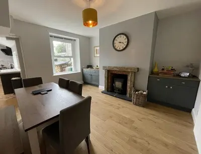 a dining room with a table and a clock on the wall at Glenderamackin Cottage in Threlkeld