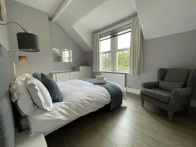 a bedroom with a bed and a chair and a window at Glenderamackin Cottage in Threlkeld