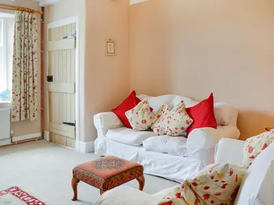 a living room with a white couch and red pillows at Field Cottage in Old Bridge of Urr