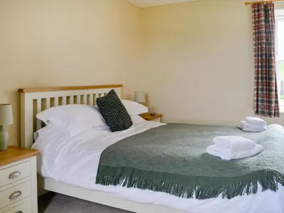 a bedroom with a bed with two towels on it at Field Cottage in Old Bridge of Urr