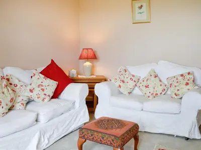 a living room with two white couches and a table at Field Cottage in Old Bridge of Urr