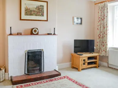 a living room with a fireplace and a television at Field Cottage in Old Bridge of Urr