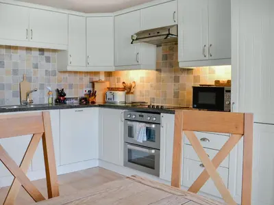 a kitchen with white cabinets and a stove top oven at Field Cottage in Old Bridge of Urr