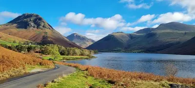 a road next to a lake and mountains at Scafell Cottage on The Big 