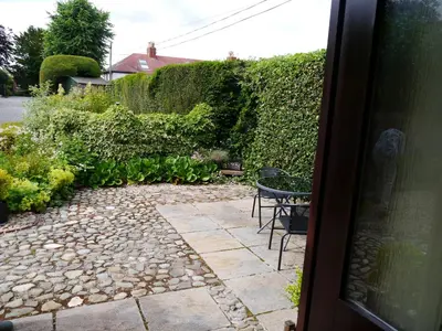 a patio with a table and chairs in a garden at Belmont Cottage in Dumfries