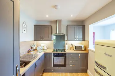 a kitchen with brown cabinets and a stove top oven at Kestrel Lodge 6 with Hot Tub in Newton Stewart