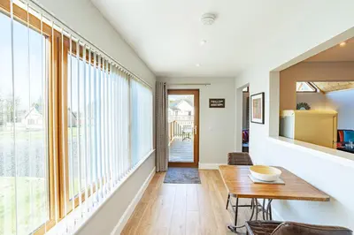 a dining room with a table and large windows at Kestrel Lodge 7 with Hot Tub in Newton Stewart
