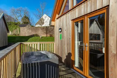 a wooden house with a hot tub on a deck at Kestrel Lodge 7 with Hot Tub in Newton Stewart