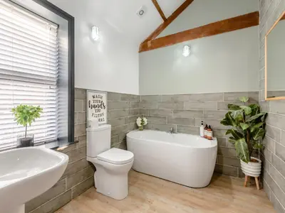 a bathroom with a tub and a toilet and a sink at The Barn Owl - Uk36217 in Bowness-on-Solway