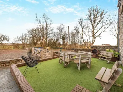 a patio with a table and chairs and grass at The Barn Owl - Uk36217 in Bowness-on-Solway