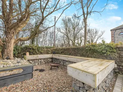 a garden with a bench and a stone wall at The Barn Owl - Uk36217 in Bowness-on-Solway