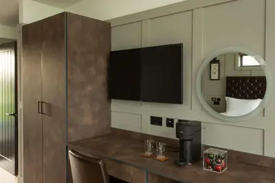 a room with a table with a television and a mirror at Dundonald Links in Dreghorn