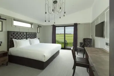 a bedroom with a large bed and a desk and a desk at Dundonald Links in Dreghorn