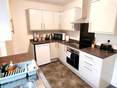 a kitchen with white cabinets and a counter top at Douglas House, near Hospital, attractive and comfy 2 bedroom House with enclosed yard to rear in Carlisle