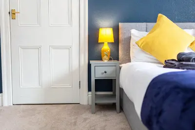 a bedroom with a bed and a lamp on a night stand at Russell House, Large townhouse spacious and modern with ground floor bedroom and shower room and free parking in Harraby