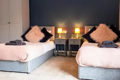 a bedroom with two beds with furry pillows on them at Russell House, Large townhouse spacious and modern with ground floor bedroom and shower room and free parking in Harraby