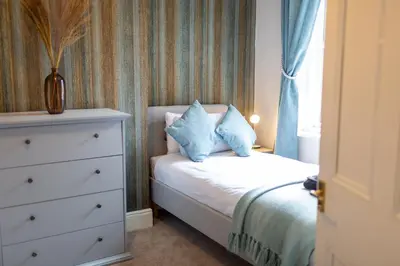 a bedroom with a bed with a dresser and a window at Russell House, Large townhouse spacious and modern with ground floor bedroom and shower room and free parking in Harraby