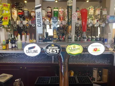 a bar with a bunch of signs on the counter at Queensberry arms hotel in Kirkconnel