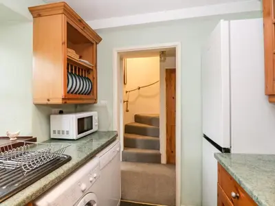 a kitchen with a microwave and a staircase at Beckfold Cottage in Broughton in Furness