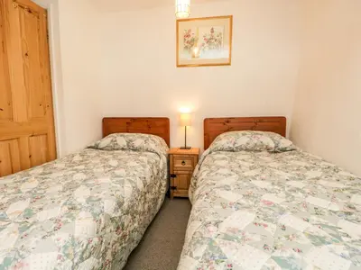 two twin beds in a bedroom with a night stand at Beckfold Cottage in Broughton in Furness