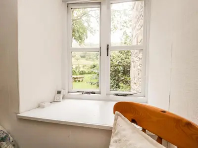 a window in a white room with a chair in front of it at Beckfold Cottage in Broughton in Furness