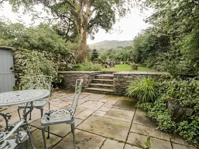 a patio with a table and chairs in a garden at Beckfold Cottage in Broughton in Furness