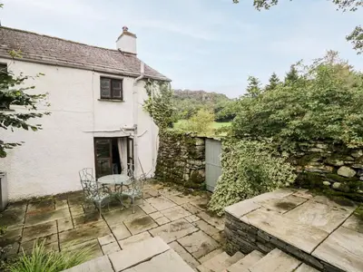 a house with a table and chairs in front of it at Beckfold Cottage in Broughton in Furness