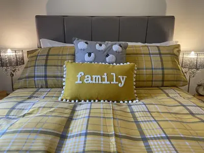 a bed with a blanket with a family pillow on it at Fairbank in Keswick