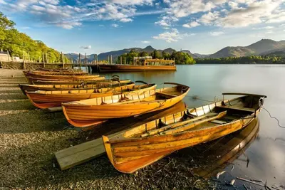 a row of wooden boats sitting on the shore of a lake at Gretaside in Keswick