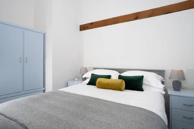 a bedroom with a white bed with green and white pillows at Grasmere Cottage with Stunnng Views by LetMeStay in Ambleside