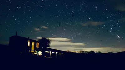 a house under a starry sky at night at Fauld O Wheat Shepherds Hut , Loch Ken ,Off Grid in Castle Douglas