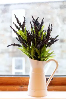 a white vase with purple flowers in a window at Prestwick Central - Donnini Apartments in Prestwick