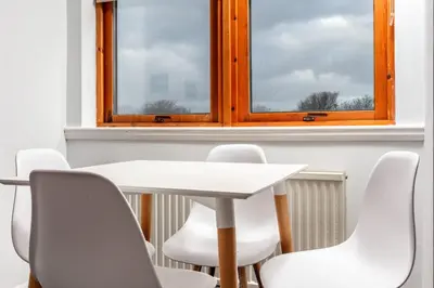 a white table and chairs in a room with a window at Prestwick Central - Donnini Apartments in Prestwick