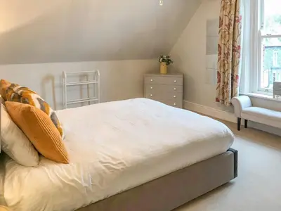 a bedroom with a white bed with a chair and a window at Upton Down in Keswick