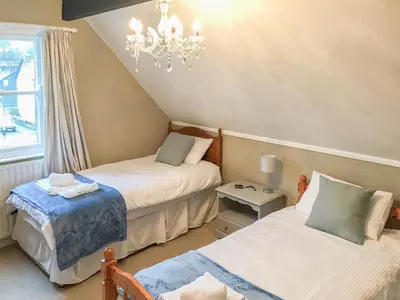 a bedroom with two beds and a chandelier at Upton Down in Keswick
