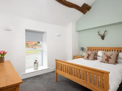 a bedroom with a wooden bed and a window at Highgate in Kirklinton