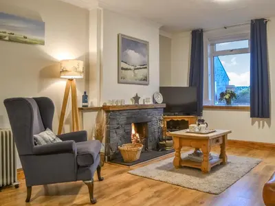 a living room with a chair and a fireplace at Catbells in Arlecdon