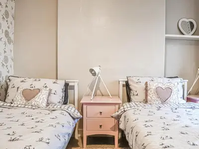 a bedroom with two beds and a night stand at Catbells in Arlecdon