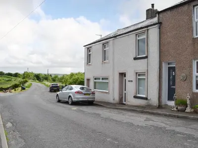 a car parked next to a house on a street at Catbells in Arlecdon